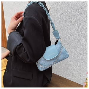 Detail of light blue denim textured underarm bag with diamond stitching and woven strap