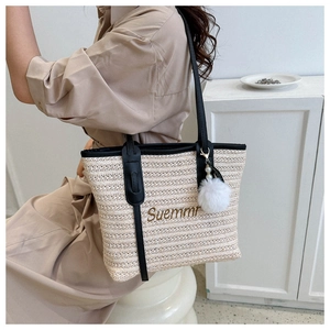 Detail of woven straw tote bag with black leather straps and embroidered Suemmr logo