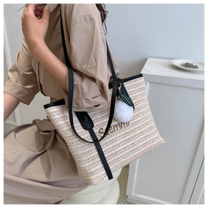 Detail of woven straw tote bag with black stripes and Summer embroidery accent