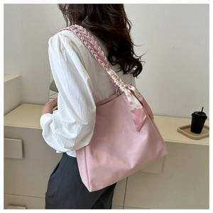 Detail of pink faux leather tote bag with braided handle and floral scarf accent