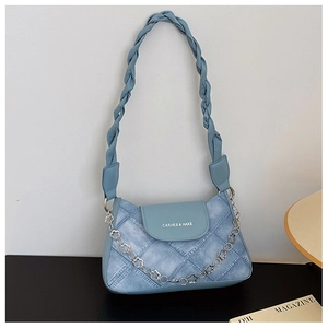 Close-up of blue denim shoulder bag featuring braided handle and floral chain detail