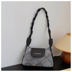 Detail of grey denim bag with quilted pattern, black leather flap and floral chain