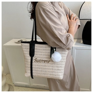 Detail of woven tote bag with Suemmr embroidery, black leather straps and plush charm