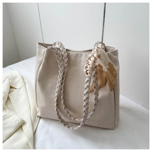 Detail of cream tote bag with houndstooth texture, woven handle and decorative silk scarf