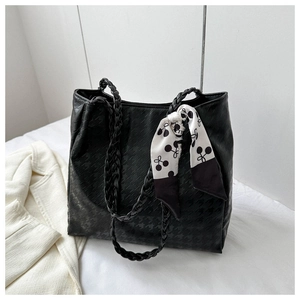 Detailed view of black tote bag featuring textured pattern and elegant silk scarf handle