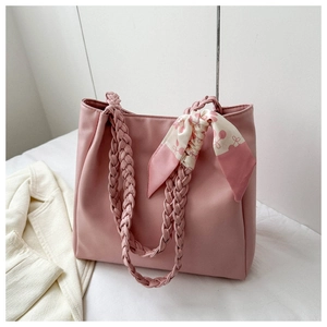 Close-up of pink PU leather tote bag with braided handles and floral scarf detail