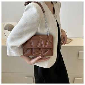 Primo piano di una borsa a tracolla in pelle marrone trapuntata con catena argentata