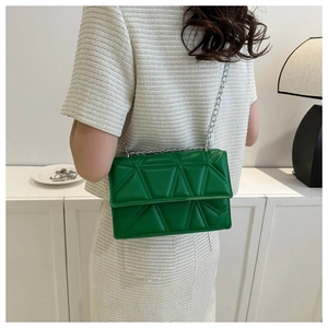 Dettaglio borsa a tracolla trapuntata verde smeraldo con catena argento su una modella