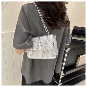 Borsa a tracolla argento con trapuntatura geometrica e catena sottile indossata dal modello