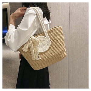 Detail of woven straw tote bag with white lace bow and decorative spiral handle base