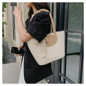 Detail of hand-woven tote bag with elegant lace bow decoration and textured handles
