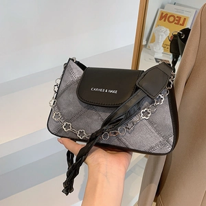 Chic denim and leather patchwork underarm bag with decorative silver floral chain