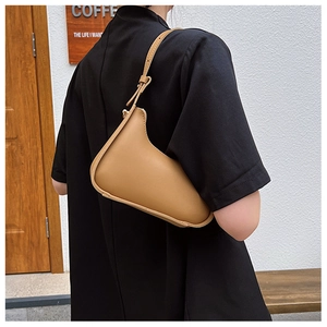 Détail d'un sac hobo marron clair porté à l'épaule dans un décor de café urbain chic