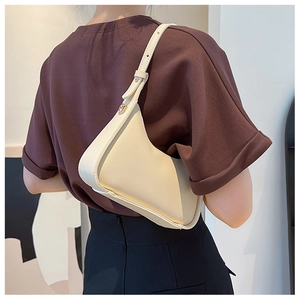 Detail of cream beige underarm bag with gold metal buckle on adjustable strap