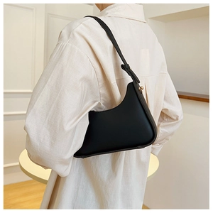 Fashionable black matte leather shoulder bag with adjustable strap on model's shoulder