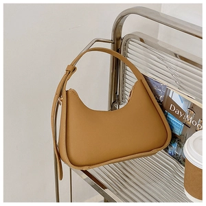 Sac hobo croissant caramel avec bandoulière réglable sur une étagère en métal