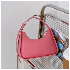 Détail du sac à main en cuir rose sur un support argenté avec accessoires lifestyle
