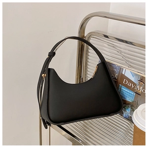 Détail du sac croissant noir mat avec bandoulière réglable et boucles dorées sur étagère