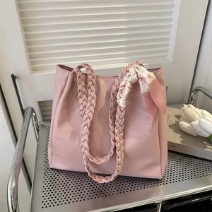 Pink large capacity tote bag with woven handles and silk scarf on a silver metal shelf