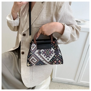 Close-up of geometric ethnic knit pattern bag with curved wooden handle and leather strap