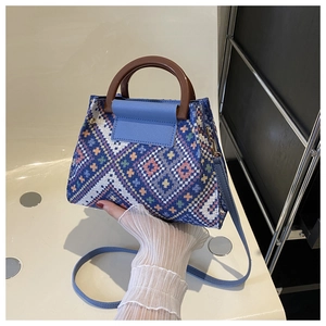 Detailed view of colorful woven handbag with wooden handle and blue leather strap