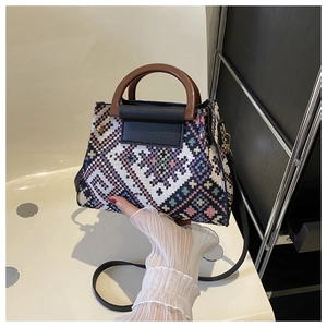 Detail of colorful geometric woven bag with round wooden handle and black leather flap
