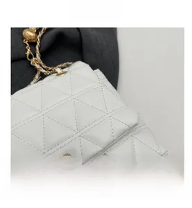 Detail of white chain bag featuring geometric triangle quilting and gold metal lock