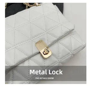 Detail shot of the golden metal twist lock on a white quilted leather crossbody bag