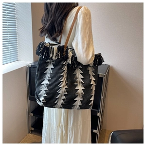 Detail of woven tote bag featuring geometric patterns, fringe edges and leather handles