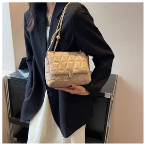 Detail of apricot quilted crossbody bag with gold chain strap on black blazer