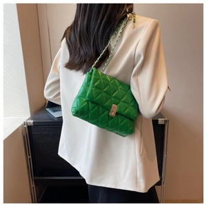 Detail of green quilted crossbody bag with gold chain strap and metal lock closure