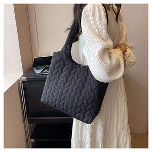 Detailed view of black quilted tote bag with leaf-like stitching texture and soft padded handle
