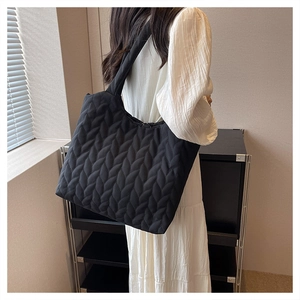 Detail of the black quilted shoulder bag featuring soft texture and large capacity