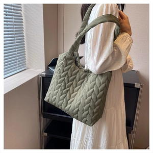 Close-up of olive green quilted tote bag with soft padded texture and wide shoulder strap