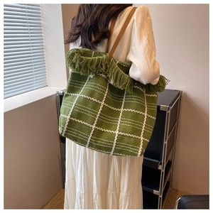 Green woven tote bag with white grid pattern, green fringes and brown leather straps