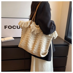 Detail of bohemian knit tote bag with beige brown geometric patterns and tassel edges