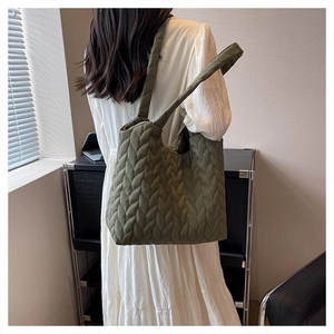 Detail view of deep green quilted tote bag with unique leaf-pattern texture on a model
