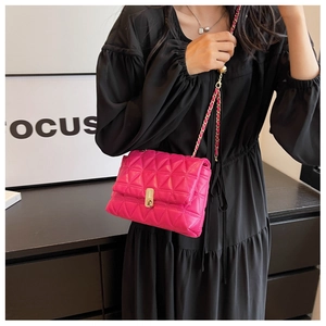 Detail of hot pink quilted crossbody bag with gold twist lock and woven chain strap