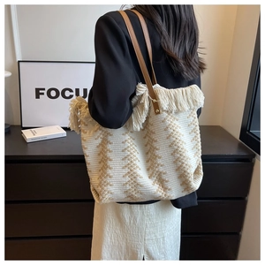 Detail of woven tote bag featuring white fringe trim and brown faux leather handles