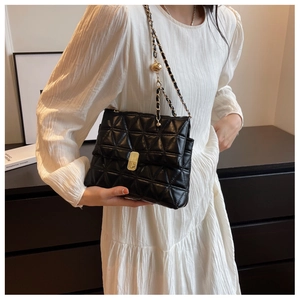 Close-up of black quilted leather crossbody bag with golden chain and ball adjustment