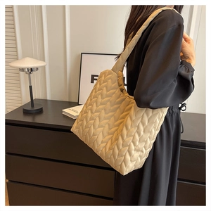 Detail of large beige quilted tote bag showing soft texture and modern wavy pattern