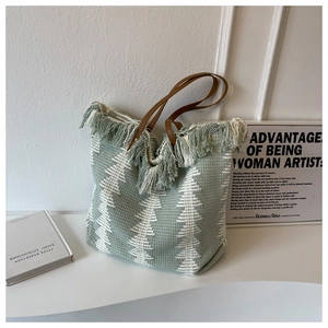 Detail of woven boho tote with sage green tree patterns and fringe tassels