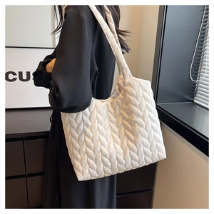 Side view of white leaf-quilted shoulder tote bag in soft material worn by a model