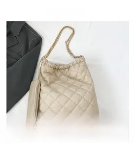 Detail of beige quilted bucket bag with chain strap and matching small zipper pouch