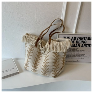 Detail of woven bucket bag with beige herringbone texture and decorative fringe trim