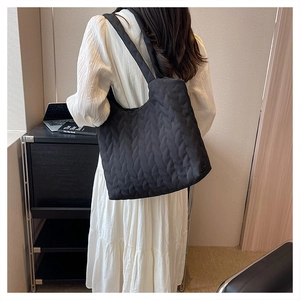 Close-up of black quilted tote bag with V-shaped stitching on soft padded fabric