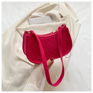 Close-up of fuchsia felt shoulder bag featuring geometric quilted patterns and gold zipper