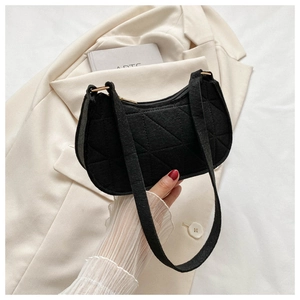 Detail of black felt underarm bag featuring geometric quilting and gold zipper accents