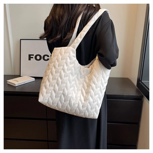 White large capacity quilted tote bag with leaf texture shown on model's shoulder