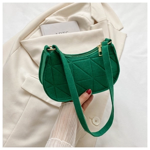 Detail of green hobo shoulder bag with geometric quilted texture on white blazer